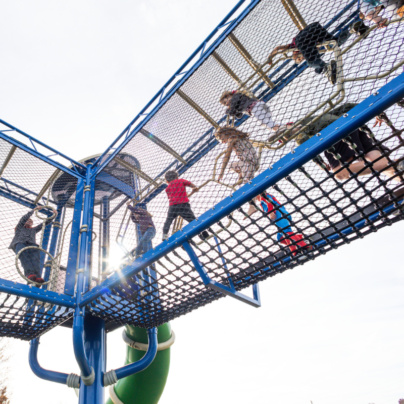 Children climbing through playground equipment.